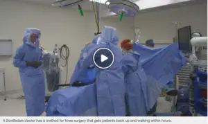 Video thumbnail — Scottsdale orthopedic surgical team performing a knee replacement procedure in a modern operating room, with caption noting patients are walking within hours of surgery