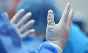 Surgeon donning sterile white surgical gloves in a hospital operating room, preparing for a procedure