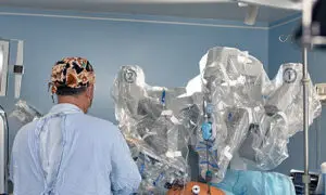 Orthopedic surgeon operating a robotic surgical system in a modern hospital operating room, viewed from behind