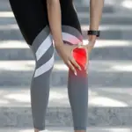 Knee pain illustration — athletic woman bending forward and clutching her knee with a red glow overlay indicating joint pain or injury