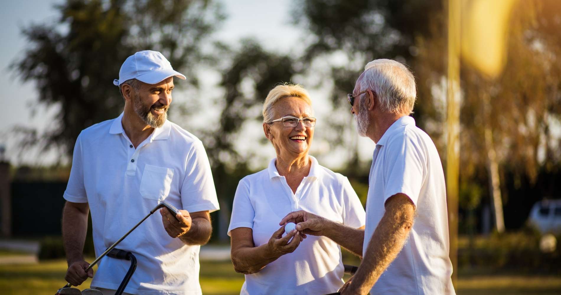 Group of older adults laughing together on a golf course at golden hour, representing a return to recreational golf and active living after hip or knee replacement surgery with Dr. Brandon Gough in Scottsdale Arizona